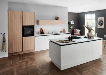 Moderne Küche mit weißen und holzfarbenden Fronten. Weiße Kücheninsel mit weißer Stein-Arbeitsplatte.