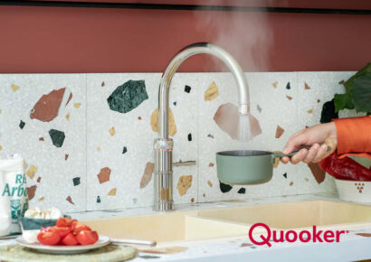 Quooker Armatur liefert kochendes Wasser direkt in einen Topf vor moderner Terrazzo Küchenrückwand