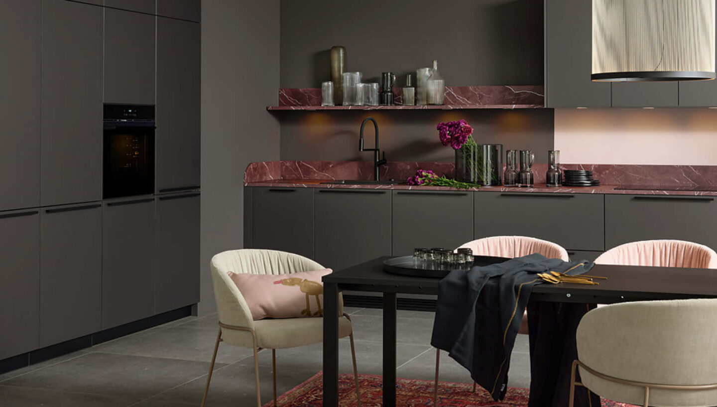 Elegante Designküche in dunklen Tönen mit integriertem Essbereich – hochwertige Materialien und stilvolle Atmosphäre