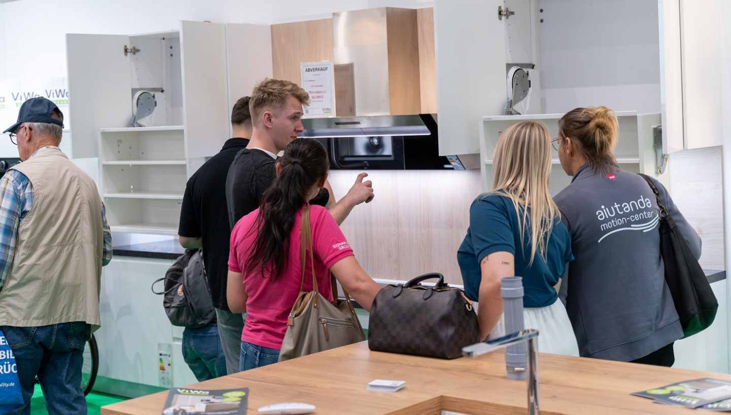 Besucher und Mitarbeitende an einer barrierefreien Musterküche von ViWa Küchen auf der IRMA Messe in Hamburg – Präsentation ergonomischer Küchenplanung mit zugänglichen Küchenschränken und individuellen Möbel-Lösungen.