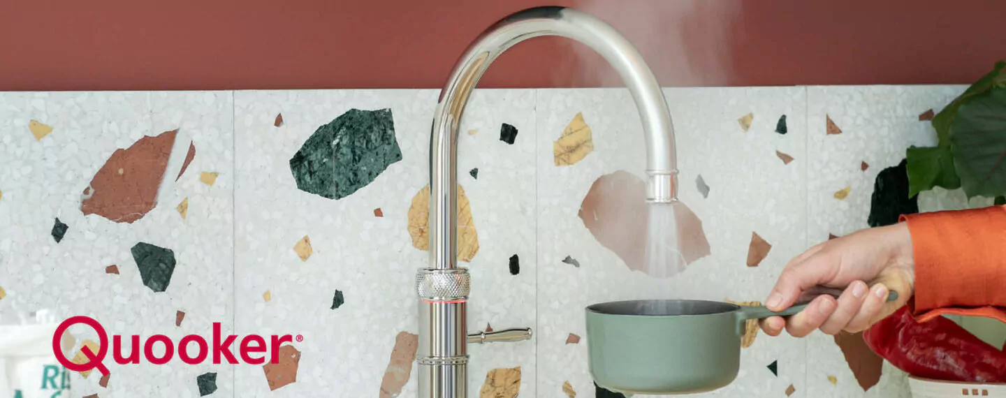 Quooker Armatur liefert kochendes Wasser direkt in einen Topf vor moderner Terrazzo Küchenrückwand